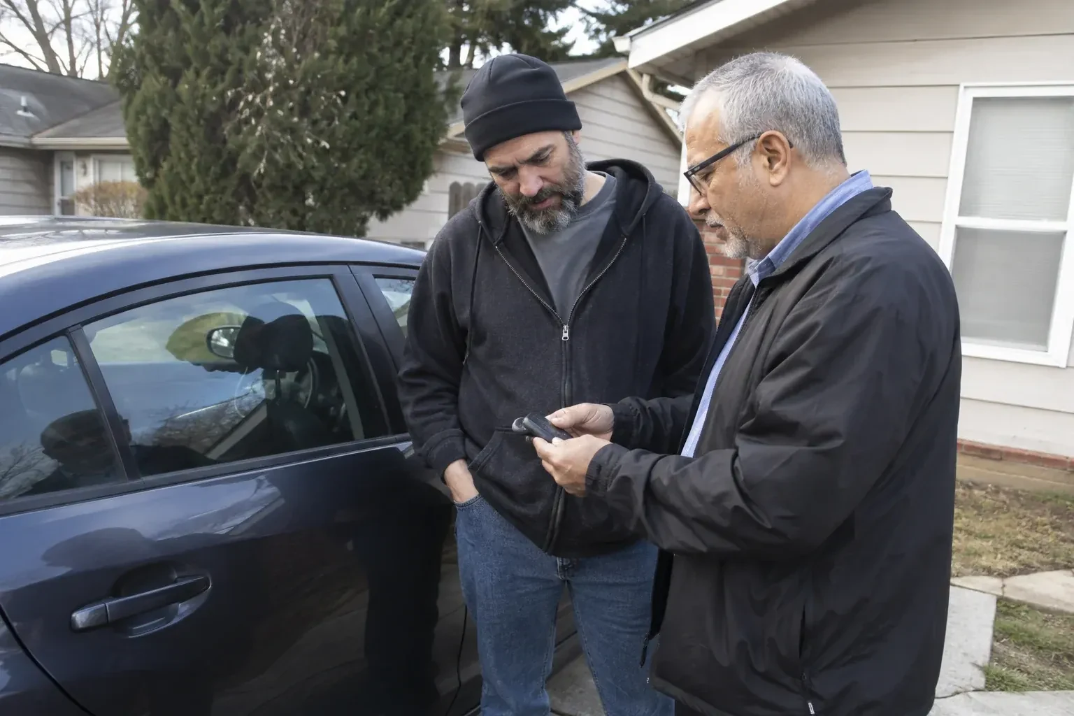 Two adults discussing a key fob beside a parked car. — Car Lockout Service, Whitby
