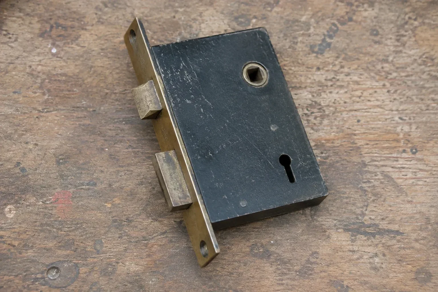 Closed mortise lock case with spindle opening, keyhole, latch and deadbolt on a wooden workbench. — Vintage Mortise Lock Service, Whitby